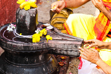 Black Stone Shivaling Of Lord God Shiva And Hands Of Hindu Holy Devotee People In Bhagwa Uniform...