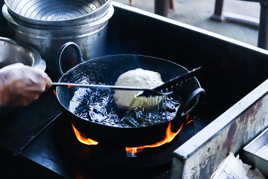 Cooking Or Deep Frying Of Famous Popular Indian Breackfast Round Fluffy Puri Or Poori In Black Wok Kadhai With And Hot Oil Spilling From Turner Or Palta