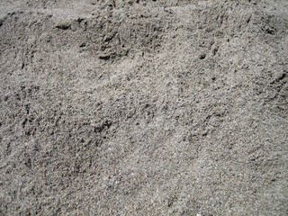 Texture of coarse-grained sea sand of gray-brown color taken from above as a texture.