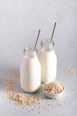Non dairy oat milk in glass jars with reusable metal straws. Healthy vegan milk alternative still life, copy space. Substitute for traditional cow milk with oat flakes, healthy lifestyle concept