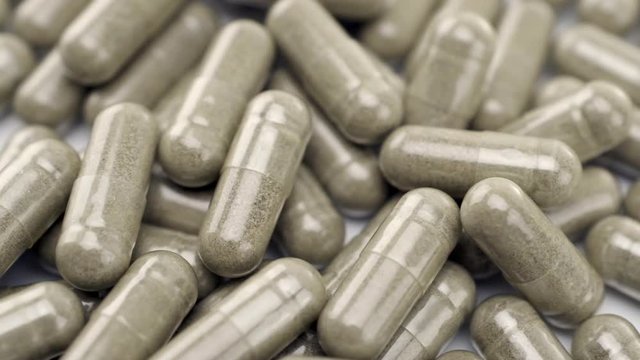 Close Up View of Natural Herbs Capsules Turning to the Right on White Background.