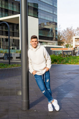 Portrait of young male with hands on pocket leaning on pole outside