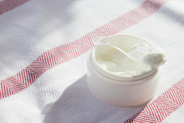 Cream in a cosmetic spoon close-up on the background of a cotton tablecloth. Spa concept, beauty salon. Minimalism.