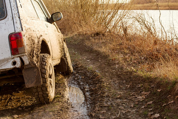 Dirty SUV is driving off-road with puddles and dirt close-up. Off-road travel © isavira