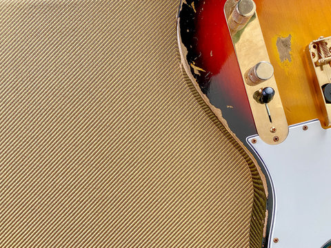 Sunburst relic electric guitar made from a genuine Alder wood on Tweed background with copy space for letter. business and music concept. Wallpaper or background.