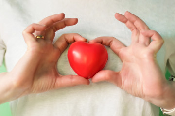 Close-up of hands holding red heart. Concept for charity, health insurance, love, international cardiology day, hope, donation and help during coronavirus covid-2019 pandemic