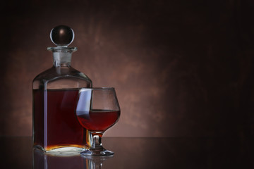 Bottle of whiskey and glass on brown background