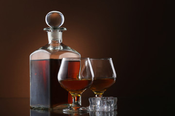Bottle of whiskey and glasses on brown background
