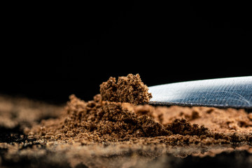 cinnamon seasoning powder on the tip of a knife and on glass on a black background