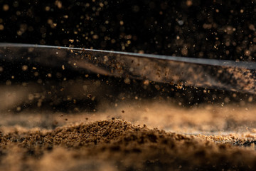 cinnamon seasoning powder on the tip of a knife and on glass on a black background