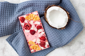  handmade pink chocolate bar with coconut, strawberry, pineapple on a grey table with