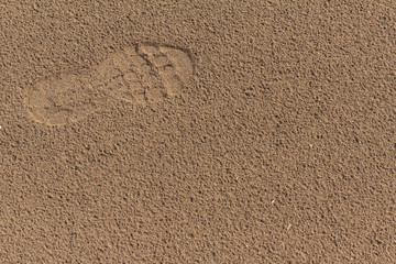Fototapeta na wymiar Footprint of a sneaker in the sand. Footstep of a human