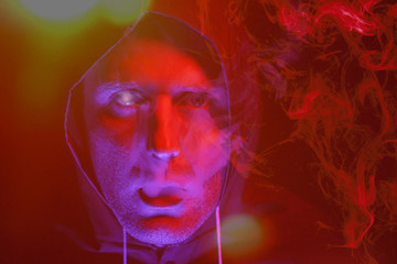 A man in a mask and chemical protection suit in red and blue light. Fight against the virus