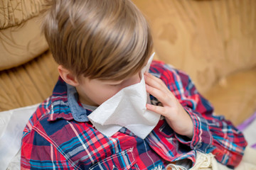 teenager blowing her runny nose in paper tissue handkerchief at home. Chronic runny nose in child....