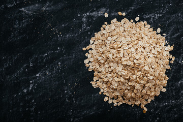 Top view of a oat flakes on a black background. healthy food concept. The image has a space to place texts or logos