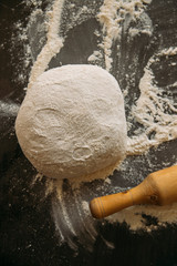 dough and rolling pin on a dark background