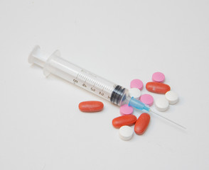 syringe with tablets of various colors and sizes