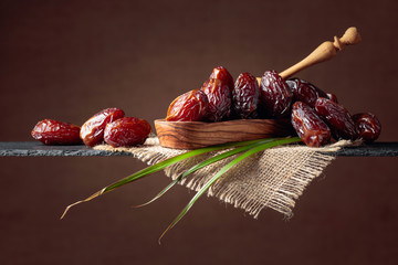  Closeup sweet dried dates in wooden dish.