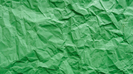 Crumpled green recycled paper, abstract background, copy space.