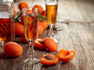 Apricot liquor and fresh apricots on a old wooden table.