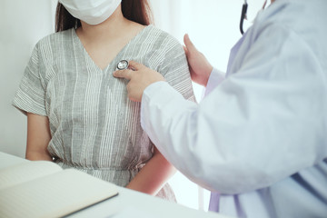 Female medicine doctor working on table with consulting patient. Wearing mask to protection from Covid 19