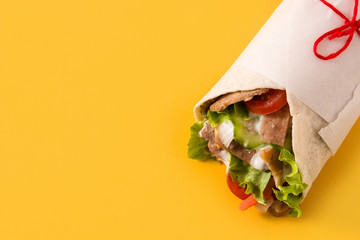 Doner kebab or shawarma sandwich on yellow background. Copy space