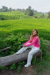 Asian woman in pink sweater sitting with rice terrace background