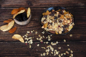 muesli with dried fruits in a black bowl on a wooden table