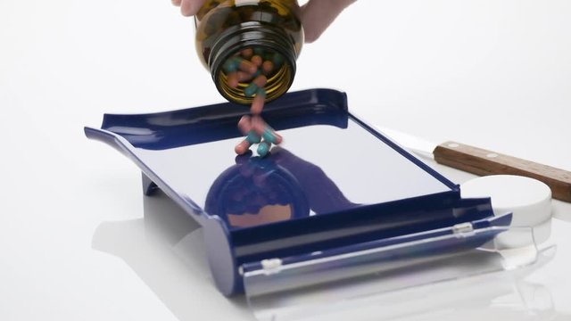 Slow Motion of Blue Teal and Pink Colored Capsules Falling from Bottle on Pharmacist Blue Counting Pills Tray