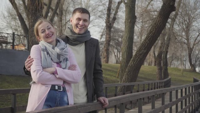 Laughing young man hugging older cheerful woman in park. Portrait of happy loving Caucasian couple with age difference dating outdoors on sunny autumn day. Love, romance, leisure, lifestyle.