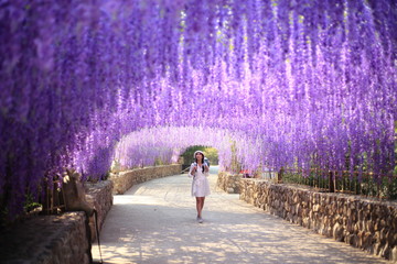 A woman walking in flower tunnel of Cherntawan International Meditation Center in Chiang Rai,...