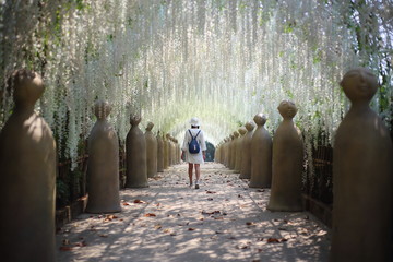 A woman walking in flower tunnel of Cherntawan International Meditation Center in Chiang Rai,...