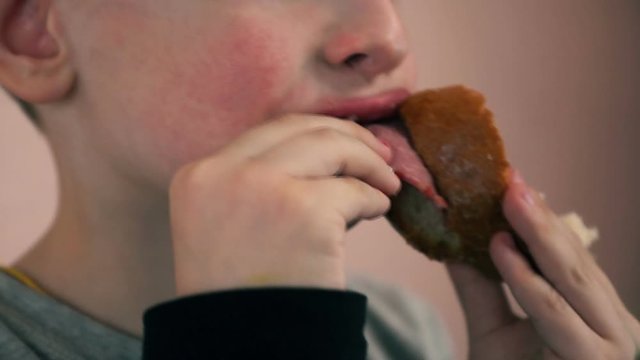 Close-up of lips and mouth of a 5-7 year old European boy biting a sandwich.
