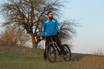 Fototapeta premium Cyclist in pants and fleece jacket on a modern carbon hardtail bike with an air suspension fork. The guy on the top of the hill rides a bike.