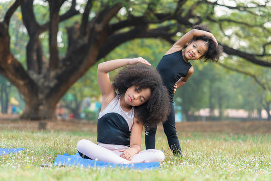 African American Older Sister And Younger Sister Practicing Yoga In The Park Outdoor