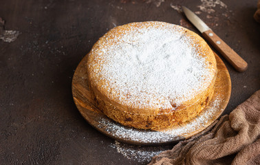 Homemade delicious sponge or soft cake on a dark brown concrete background. Freshly baked...
