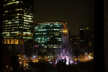 Streets of Mexico City at night painted with golden lights illuminating the buildings in the city with a city landscape
