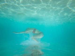 Fototapeta na wymiar Under water photo of a woman in bikini diving in turquoise sea w