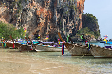 many moored boats on the shore against the background of rocks