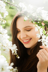 portrait of a dreamy smiling girl with closed eyes in a blooming garden