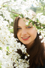 Portrait of a smiling girl with blue eyes in a blooming garden