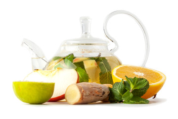 isolated glass transparent teapot with tea from ginger root, lime, orange, apple, mint on a white background