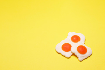 Three jelly fried eggs on the left on a yellow background, close-up. Sugary photo for your delicious design.