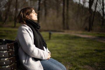 pregnant woman in spring on park bench