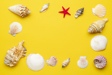 Summer background beach with shells and starfish in shape frame isolated on yellow backdrop. Top view travel or vacation concept