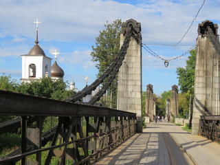 Russia. Pskov region. City Ostrov.  The Great River. This suspension bridge is 100 years old.  There is a temple on the Bank of the Great river. 