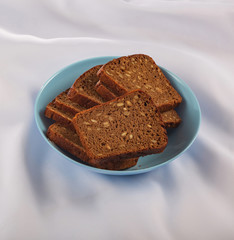 Healthy food. Sliced dark bread with grains in a blue plate
