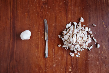 White mushrooms on an old wooden table are sliced and arranged.