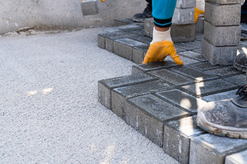 Workers lay paving tiles, construction of brick pavement, close up architecture background stock photo...