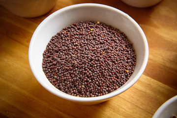 Obraz na płótnie Canvas brown mustard seeds in white bowl on wooden background